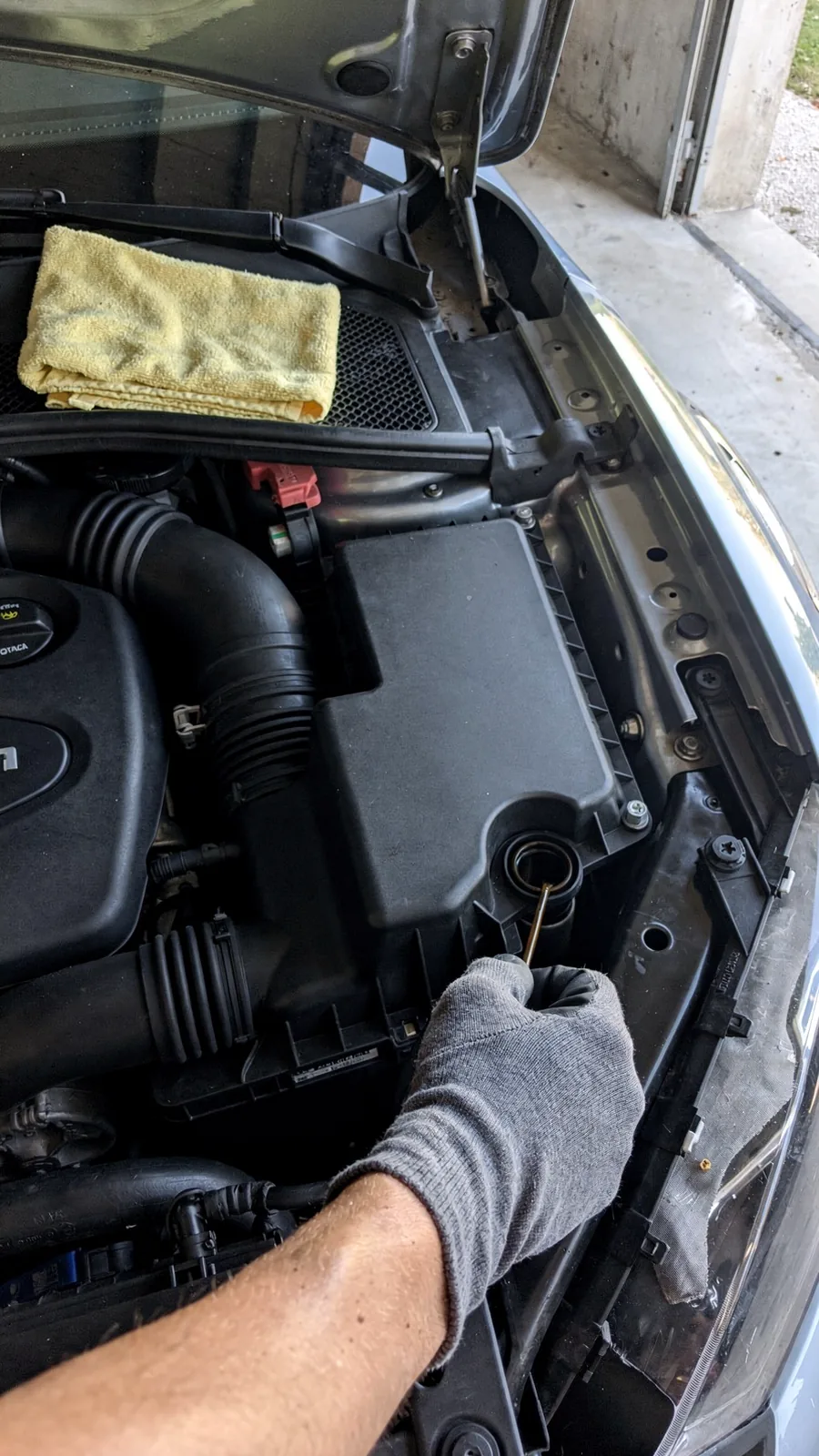 Ruka u radnoj rukavici izvlači šipku za mjerenje ulja iz motornog prostora